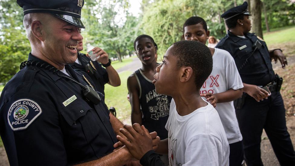 Officer Jim Lopez (L), of the Camden County Police Department (CCPD), wrangles with Omar Headen, age 13, during a day of action, organized by the CCPD, which included neighbourhood interaction and the cleaning of Farnham Park, on August 22, 2013 in the Parkside neighbourhood of Camden, New Jersey.