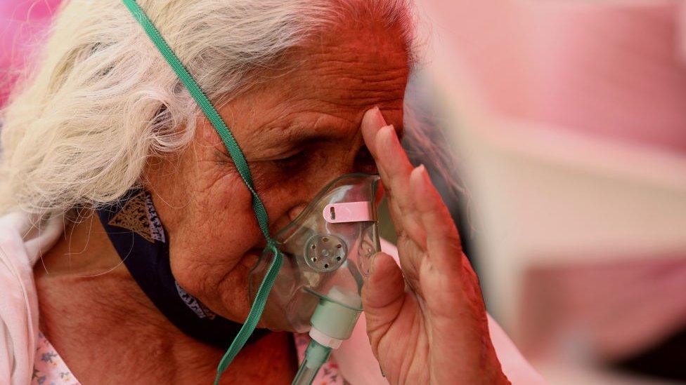 A Covid-19 patient who is suffering from breathing difficulty breaths with the help of oxygen mask outside Gurudwara.