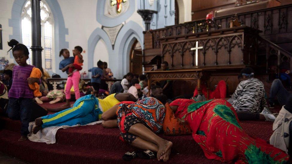 People are seen sleeping on the steps, after a scuffle broke out earlier in the day, inside the Methodist Church in Cape Town on 15 November.