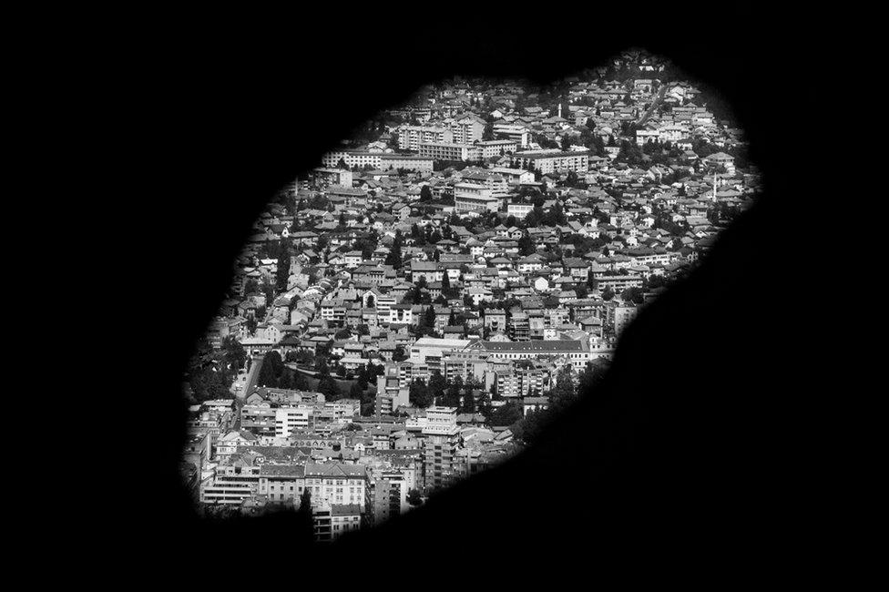 A view through a hole in a wall on to a city landscape