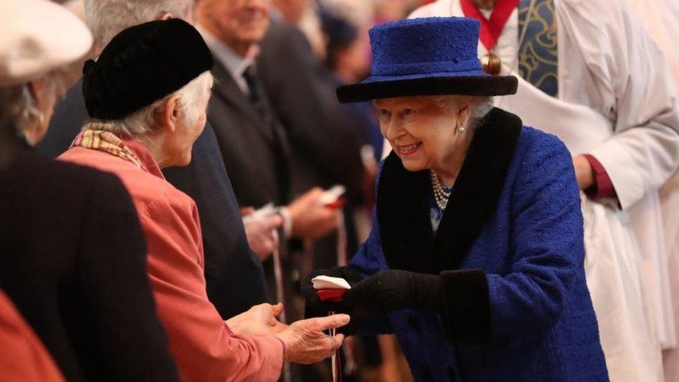 A smiling Queen Elizabeth hands out Maundy money