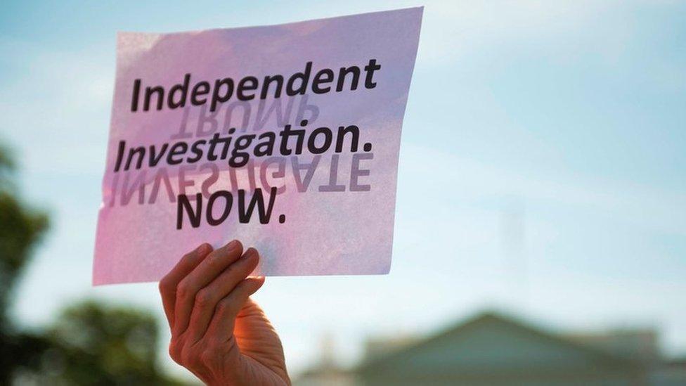 This file photo taken on May 10, 2017 shows a protester holding a placard in front of the White House during a protest demanding an independent investigation in the Trump/Russia ties after the firing of FBI Director James Comey in Washington, DC