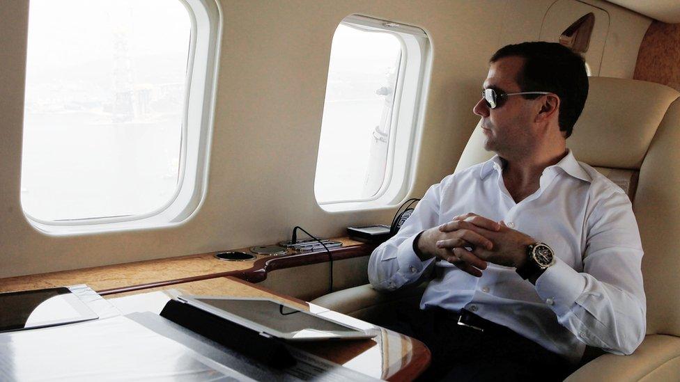 Dmitry Medvedev looks through a helicopter's window, with an iPad on a table in front of him