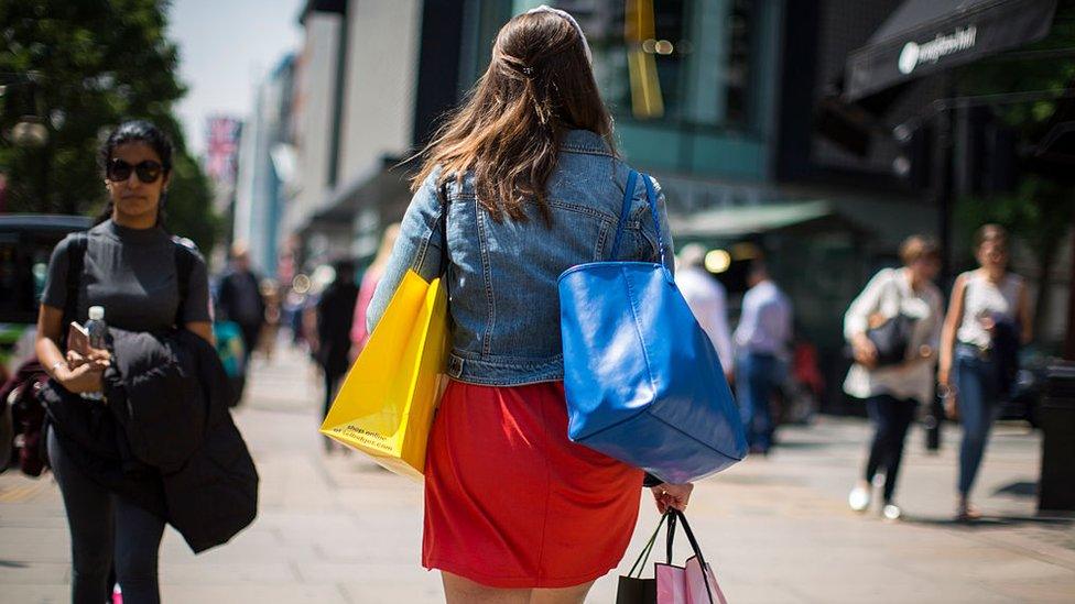 A shopper carries her bags along Oxford Street, London