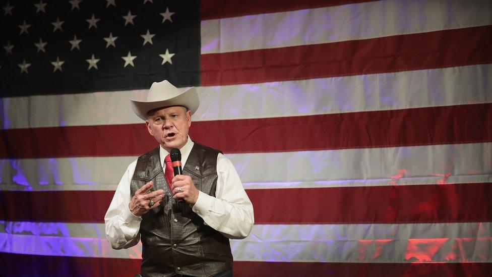 Roy Moore standing giving speech in front of American flag