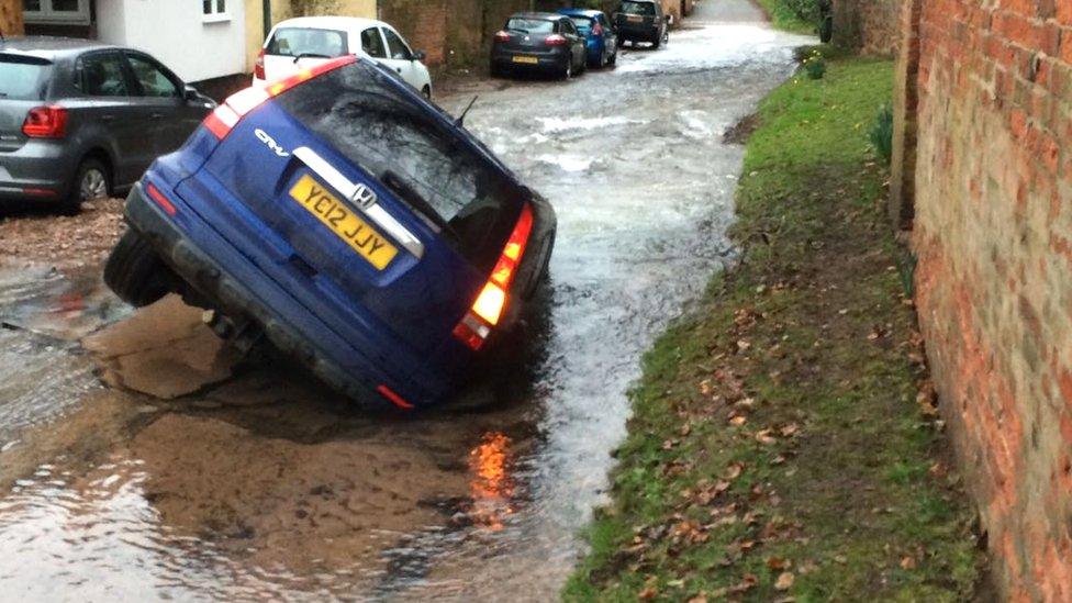 Car in a sinkhole created by a burst water main