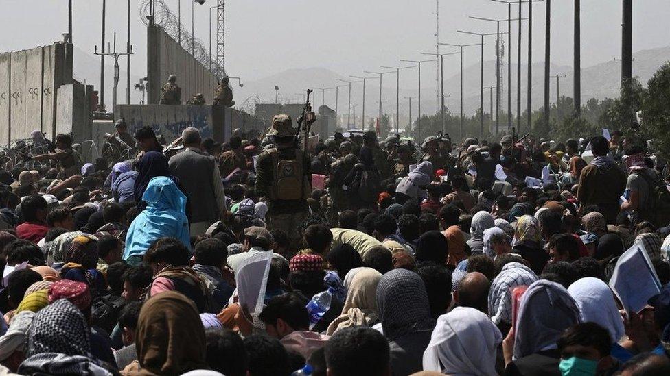 A crowd of people waiting on the roadside outside Kabul airport, trying to leave the country in August 2021