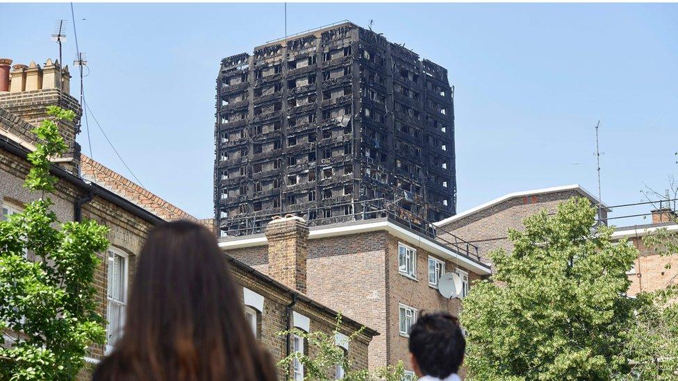 people looking at burnt out grenfell tower