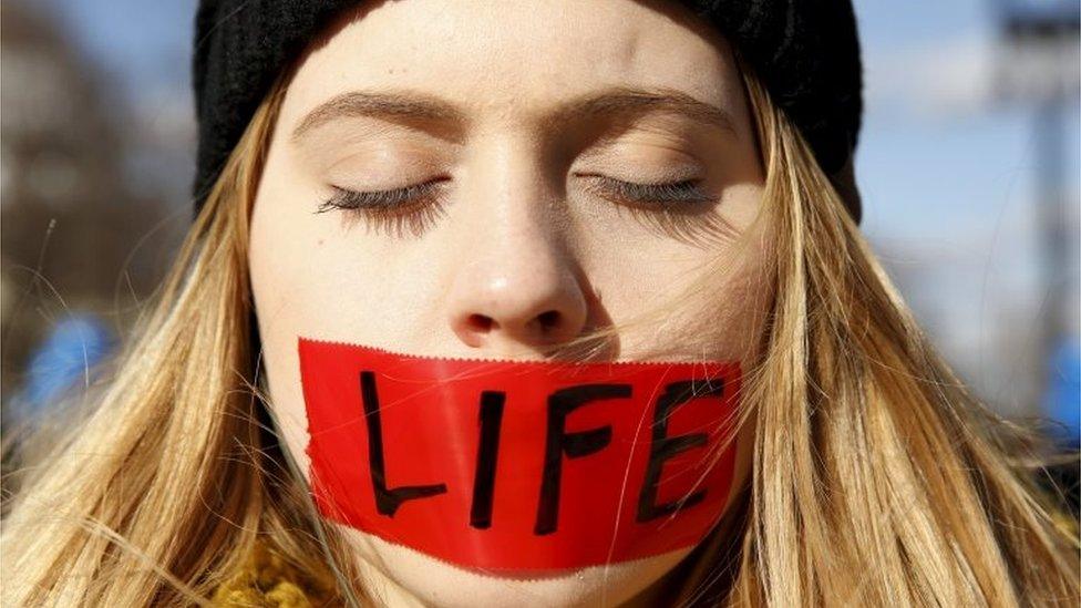 A protester with her mouth taped over with the word "life" stands in front of the US Supreme Court on 2 March