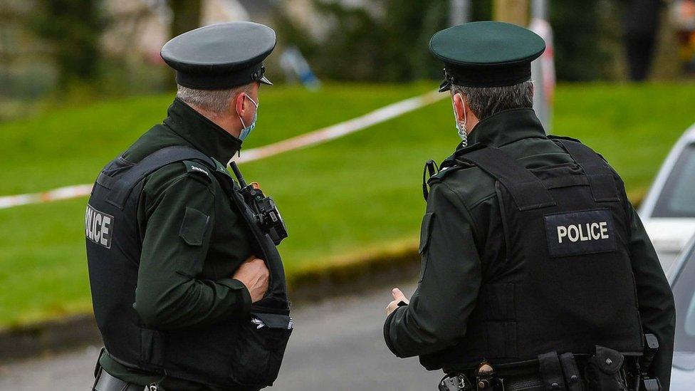 Two police officers stand at a cordon