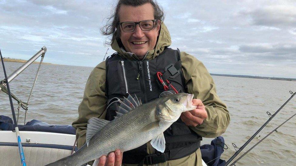 David Mitchell from the Angling Trust holds up a bass he's caught