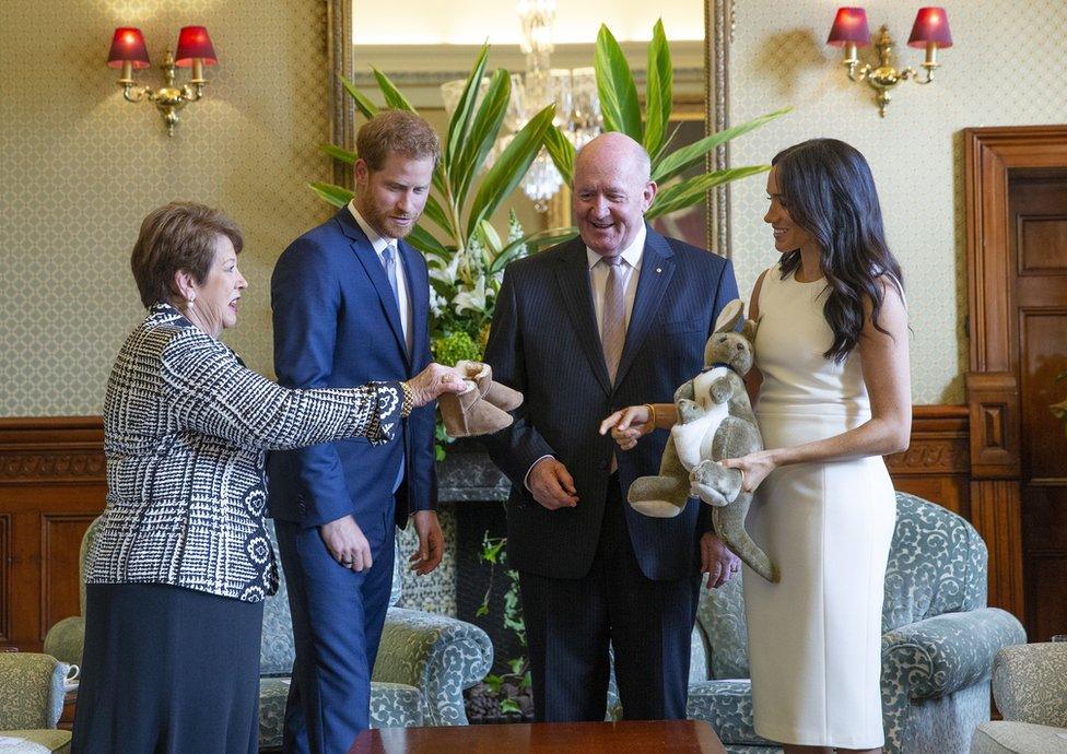 Australian Governor-General Sir Peter Cosgrove (2-R) and his wife Lady Cosgrove (L) present a toy kangaroo and a pair of small ugg boots to Britain"s Prince Harry (2-L), the Duke of Sussex, and his wife Meghan (R), the Duchess of Sussex, during an event at Admiralty House in Sydney, Australia, 16 October 2018