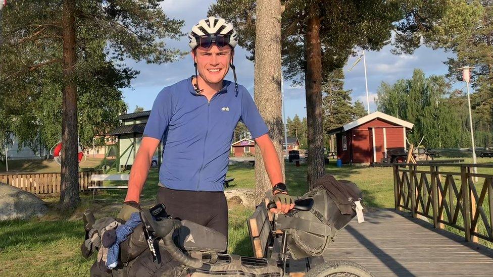 Kieran Payne stood in cycling gear holding his bike