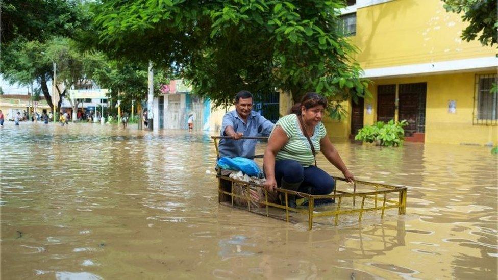 Two people try to advance along a street flooded by the Piura river in Piura, Peru, 27 March 2017.