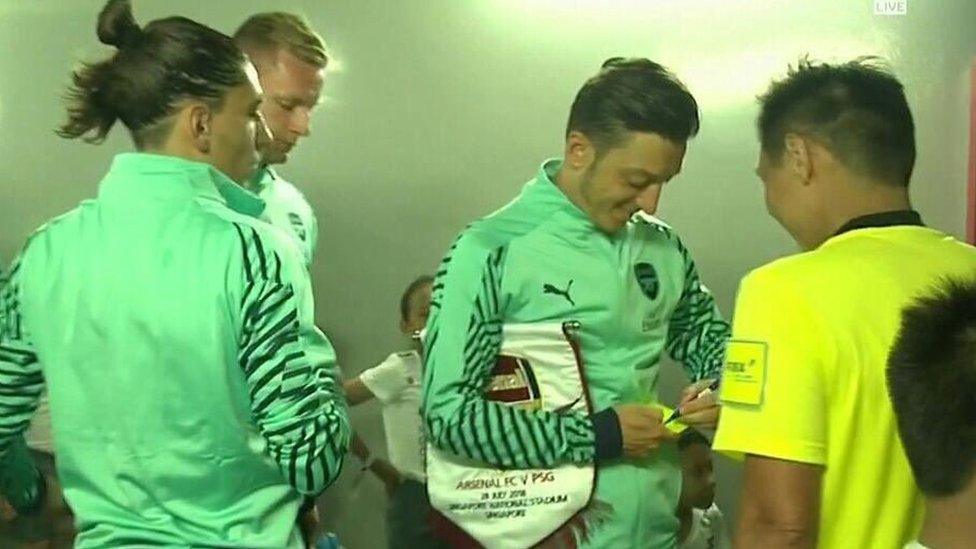 Mesut Ozil signs a yellow card