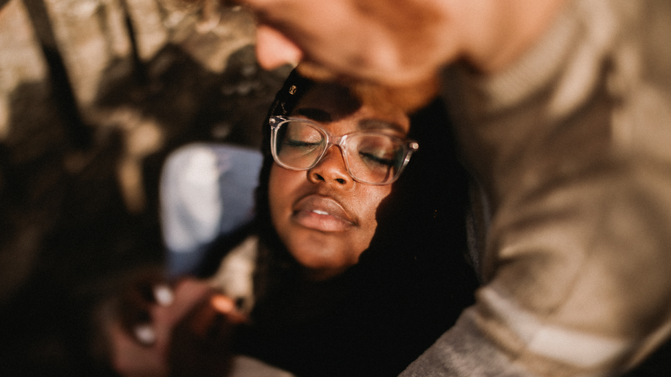 This photo is of woman in the arms of her partner, with just her relaxed happy face in focus