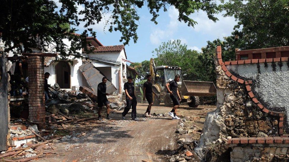 Police officers walk at the residence of Panama's former dictator Manuel Antonio Noriega, currently imprisoned in Panama, Panama City, as it is being demolished on January 9, 2014 following a decision by the Health Ministry for considering it a breeding site of the Aedes mosquito that transmits dengue.