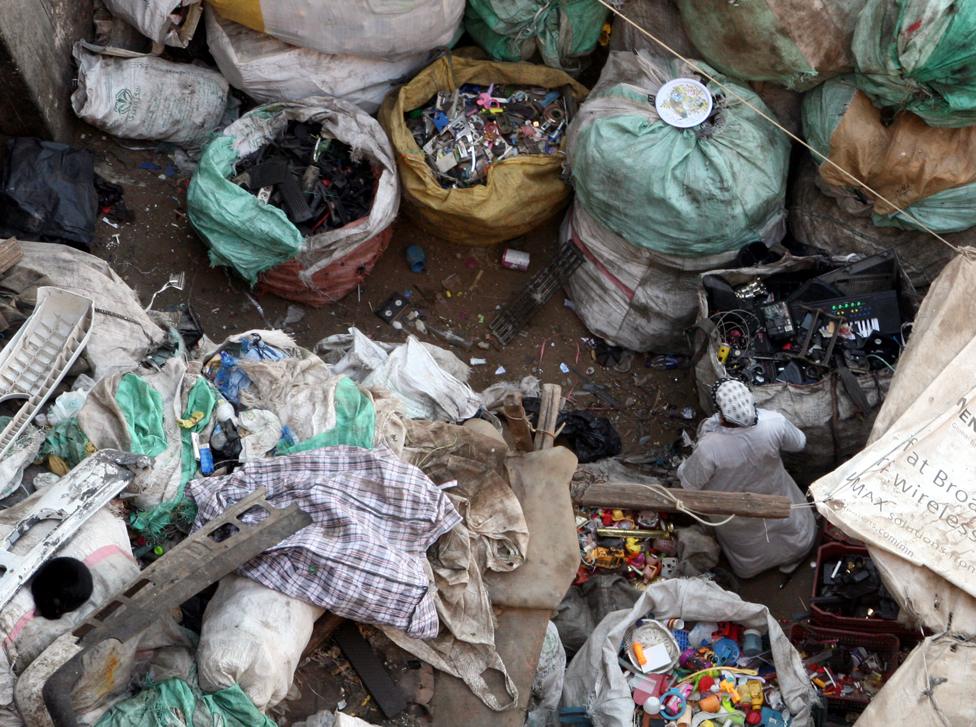 a woman making her way amid various garbage bags inside a courtyard of a house in the Zabbaleen area (Garbage city), in Cairo, Egypt,