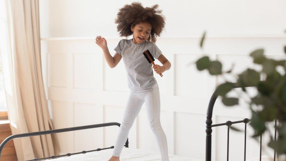 Girl-bouncing-bed-singing-hairbrush.