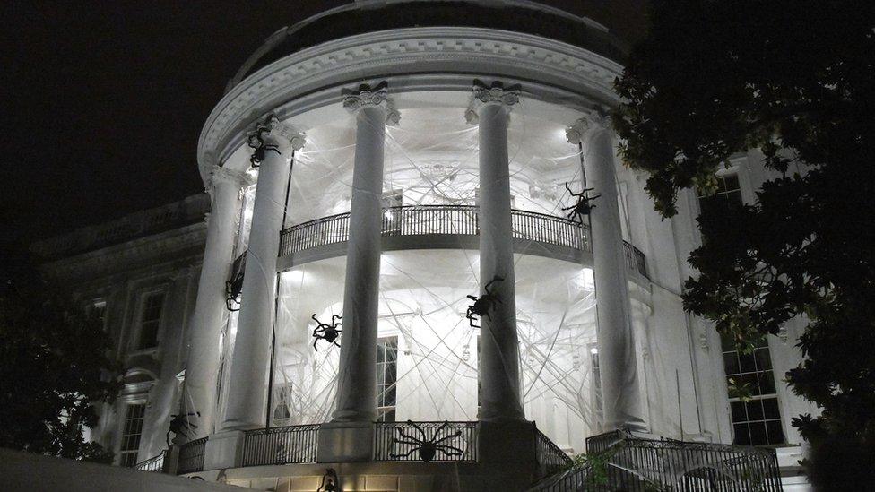 The White House at night decorated with fake cobwebs and spiders.