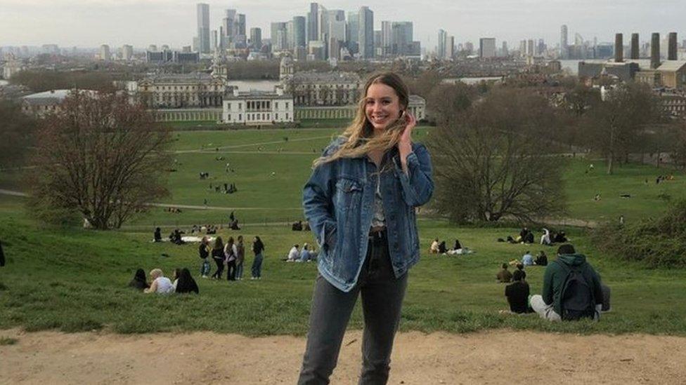 Ella Watson stands on a hill with the City of London behind her