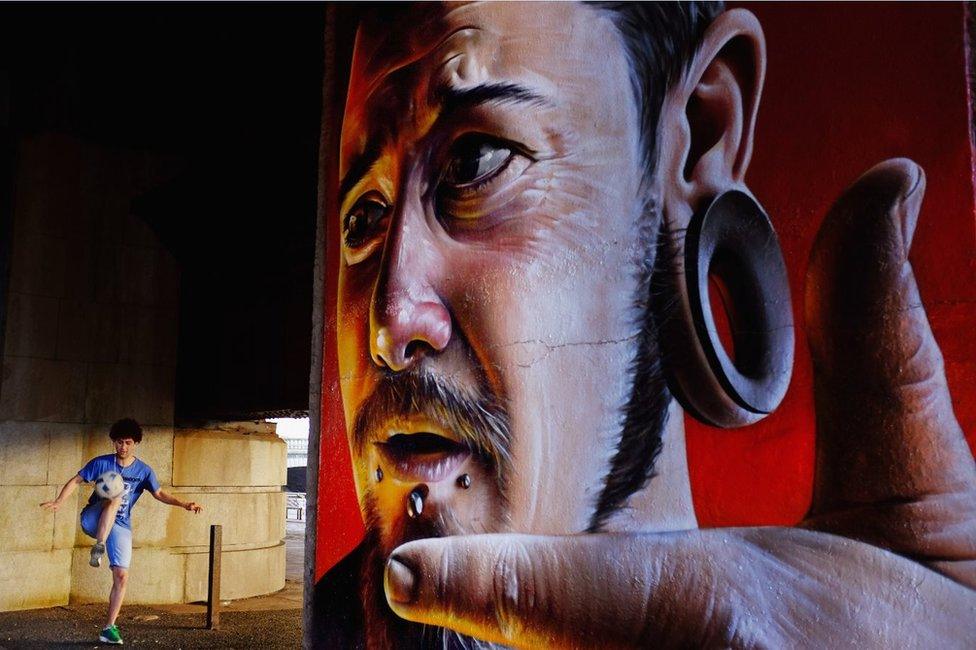 Boy plays football next to mural on Caledonian Railway Bridge in Clyde Street