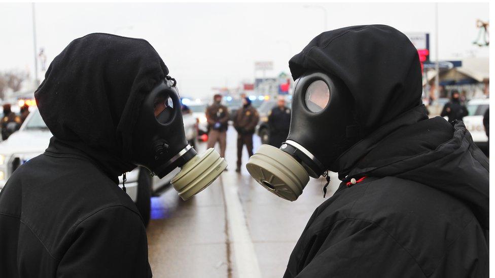 Two protesters in gas masks.