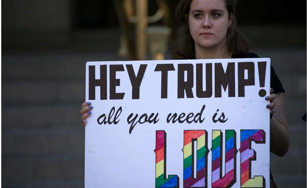 A protester holds a sign in front of the new Trump International Hotel on Pennsylvania Avenue in Washington, DC, USA, 12 September 2016