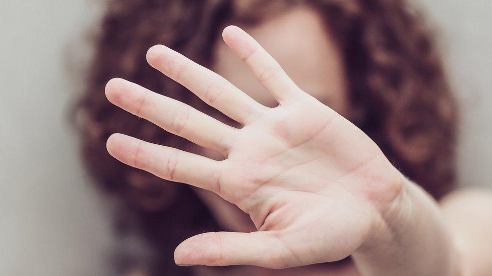 File photo of a woman holding her hand up in a protective stance