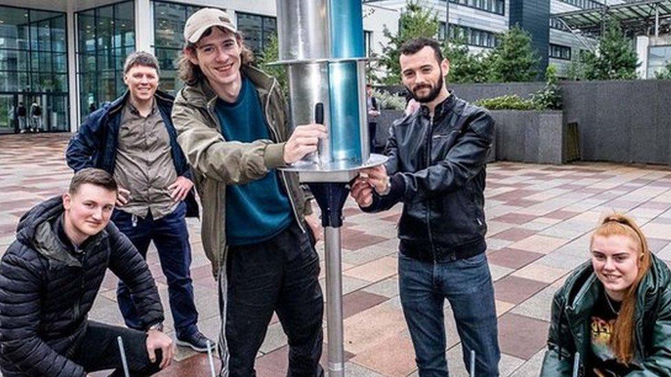 Students holding a flatpack wind turbine with solar panels