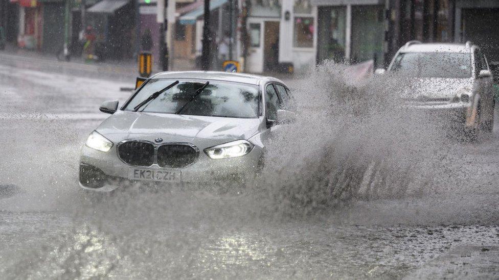 A car driving through a flooded section of road