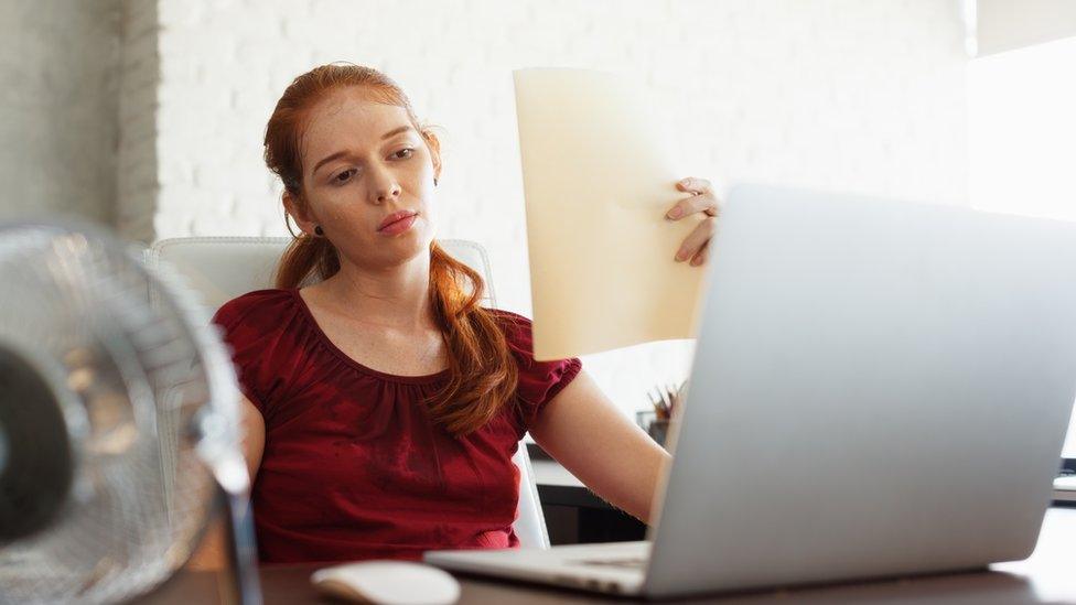 A woman trying to cool down at her desk