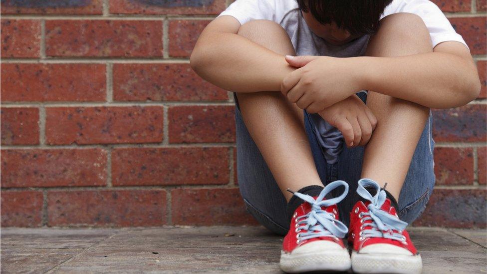 Upset-boy-sitting-against-a-wall