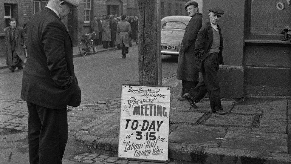 Man looking at a poster for a meeting about unemployment in Derry