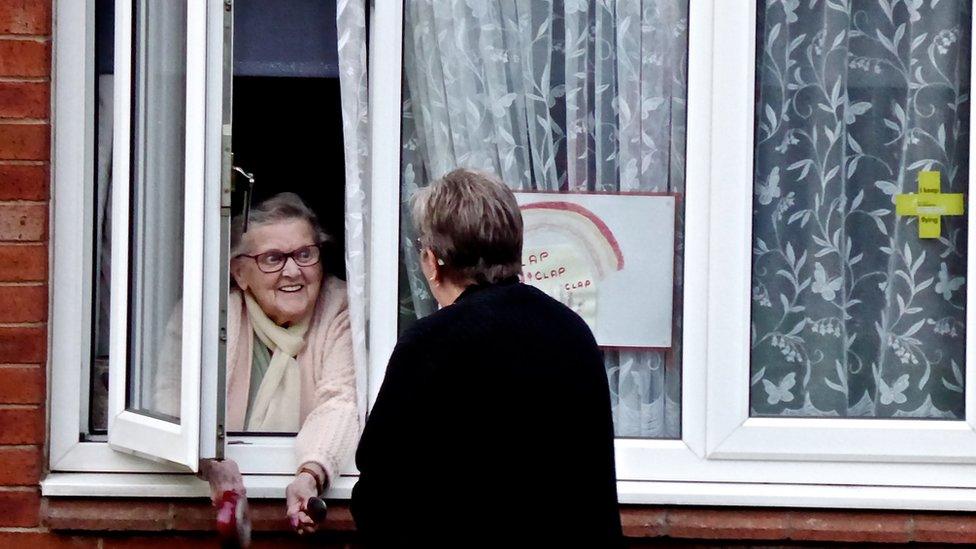 Two women talking at a window