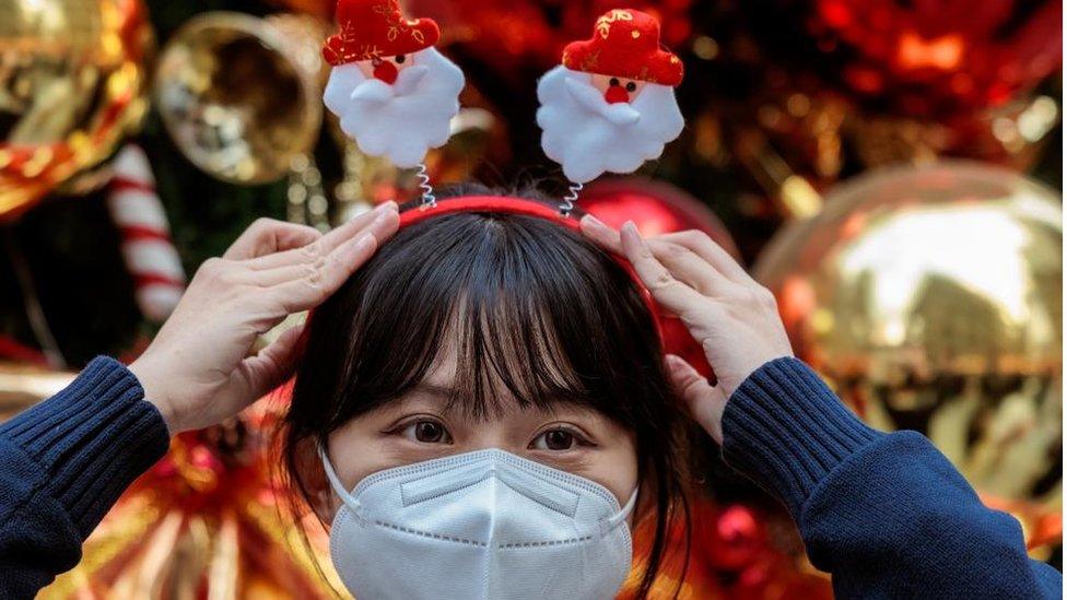 A woman adjusts her festive headband at a Christmas market in Shanghai, China