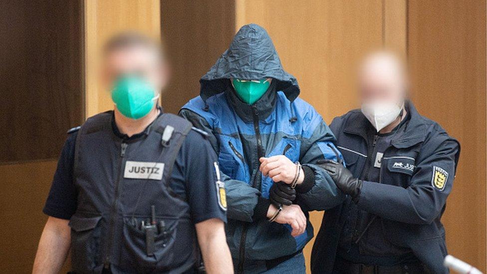 A defendant is escorted into court by two officers