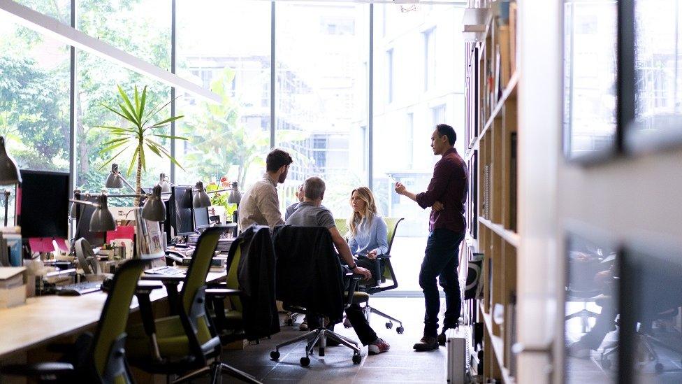 business people discussing in office. Male and female professionals are working together at workplace. They are wearing smart casuals.