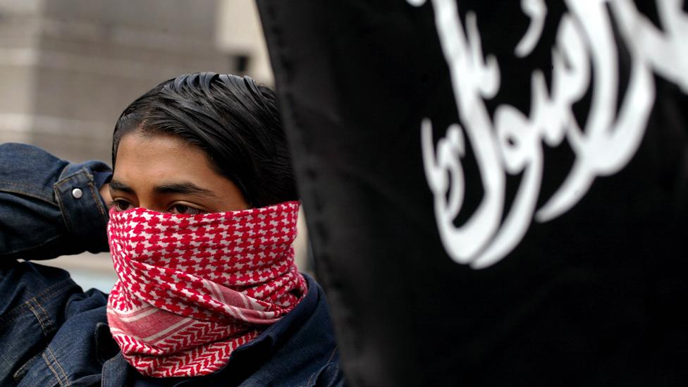 A boy ties on a scarf to hide his face August 25, 2002 during a 'Rally For Islam' demonstration held by al-Muhajiroun