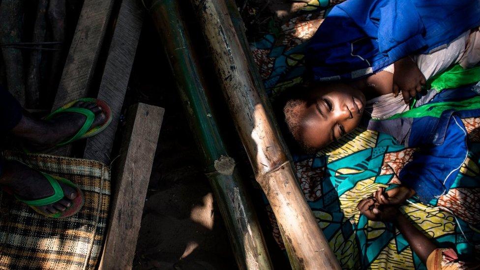 A boy rests with other Internally Displaced Persons (IDP's) as they wait for their daily food ration in a site for IDP's fleeing the conflict in the Kasai Province on June 7, 2017 in Kikwit