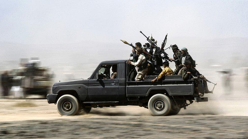 Armed Yemeni tribesmen loyal to the Houthi rebels sit in the back of an armed vehicle