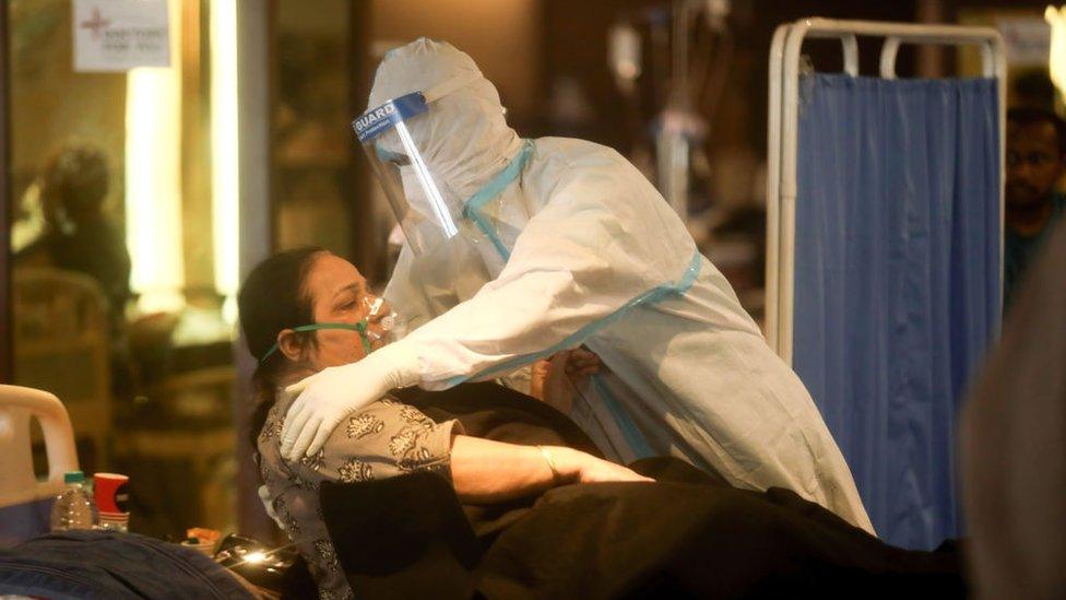 A health worker wearing a protective suit helps a patient inside a Covid-19 care center, a banquet hall temporarily converted into a coronavirus Covid-19 ward for coronavirus patients.