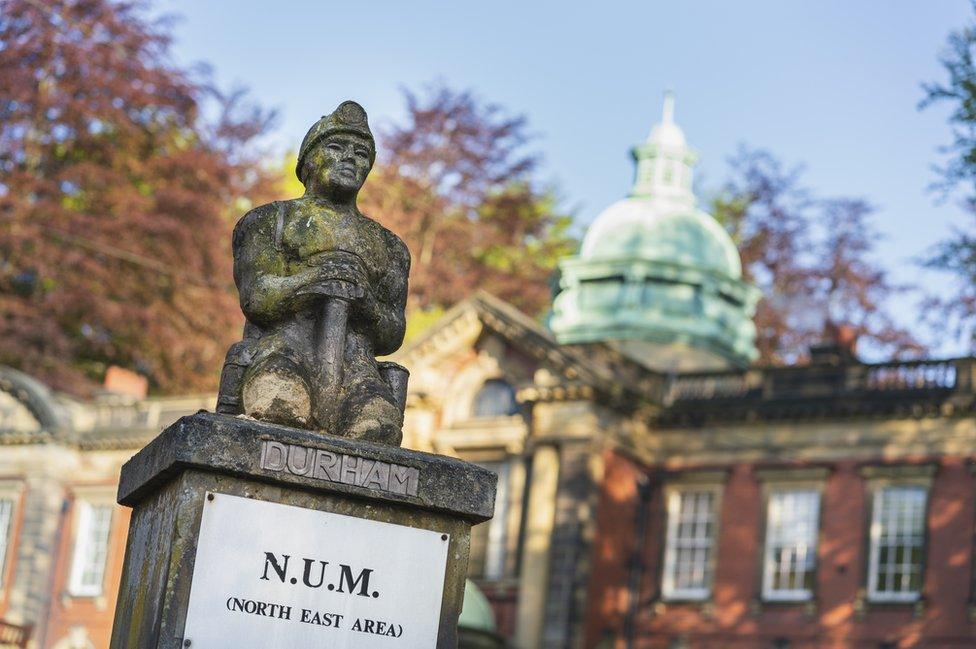 A small stone sculpture of a miner with Redhills in the background