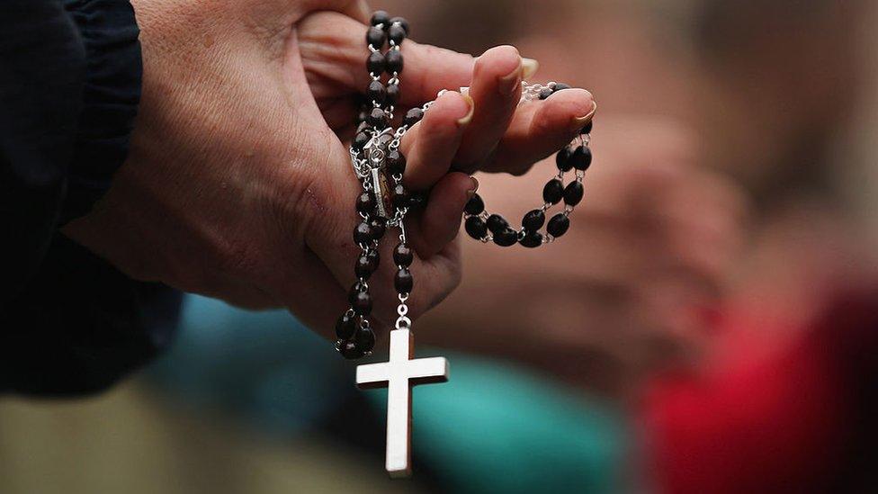 A woman holds rosary beads