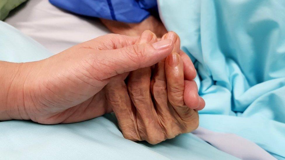 nurse holding patient's hand in hospital