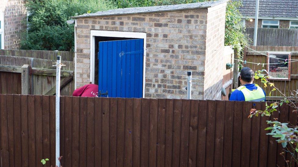 Officers inspect outhouse