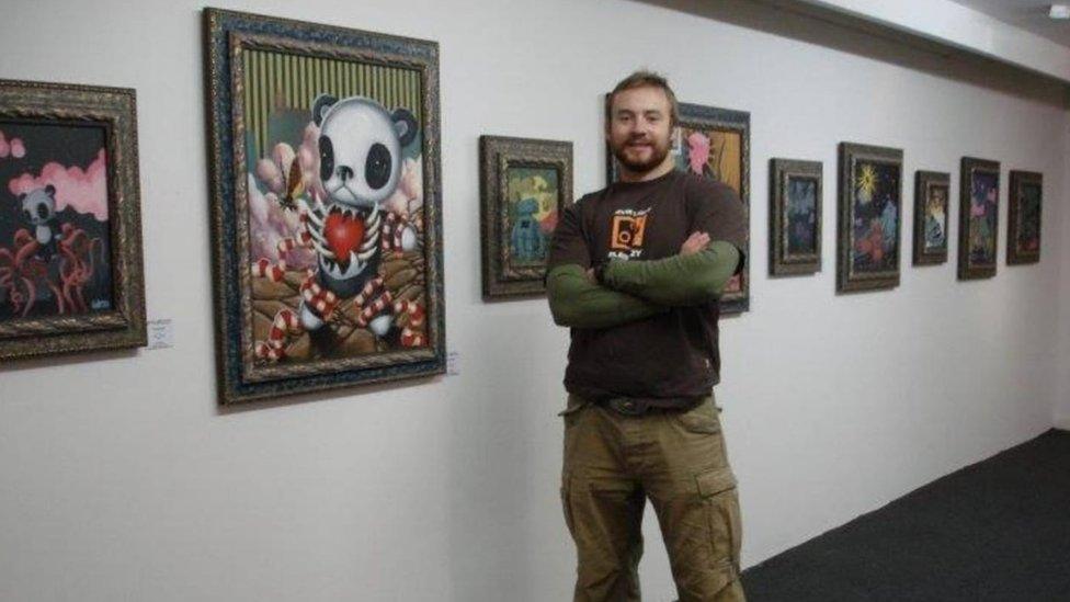 Pip Holmes standing with his artwork