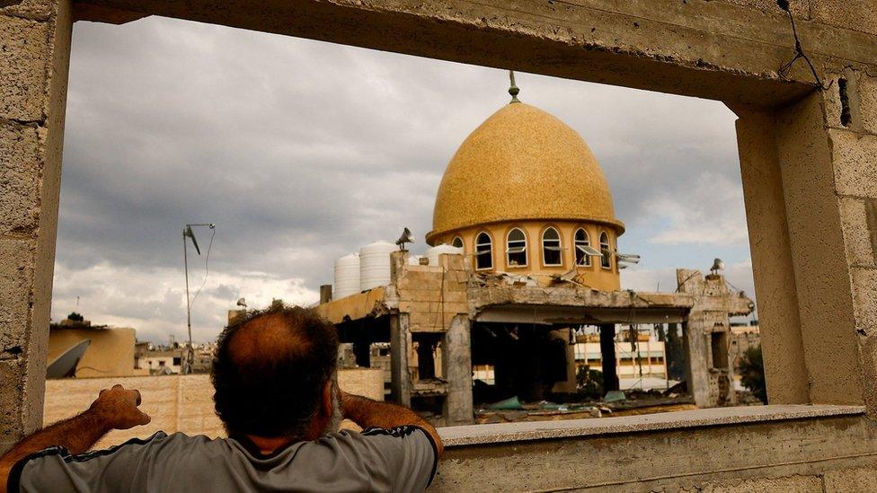 A Palestinian man looks at a mosque damaged in an Israeli air strike in Khan Younis, in the southern Gaza Strip (15 November 2023)