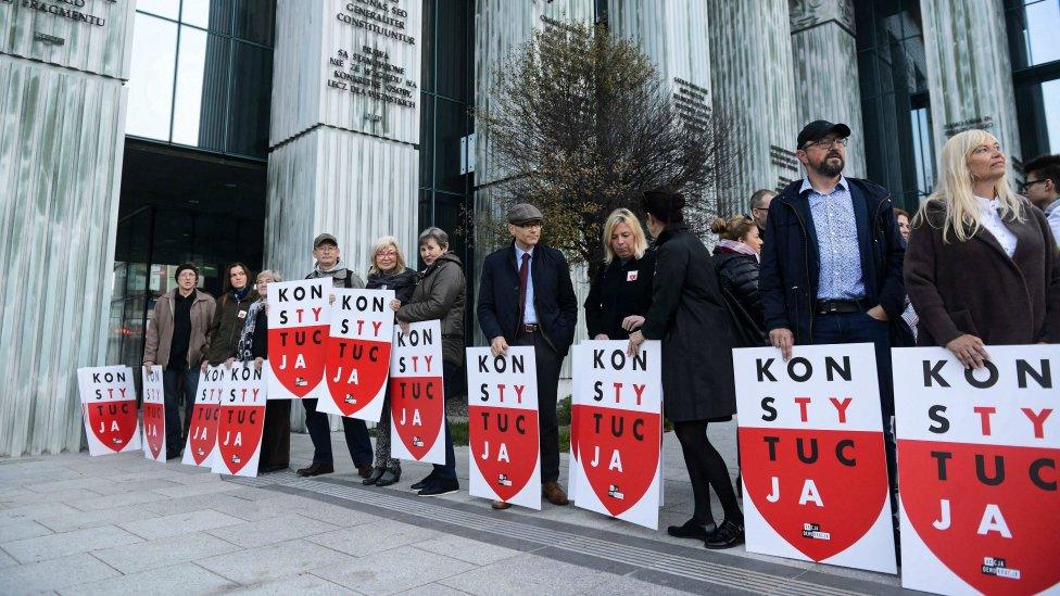 People hold placards "Constitution" during their protest in front of the Supreme Court building in Warsaw, Poland, 11 October 2018