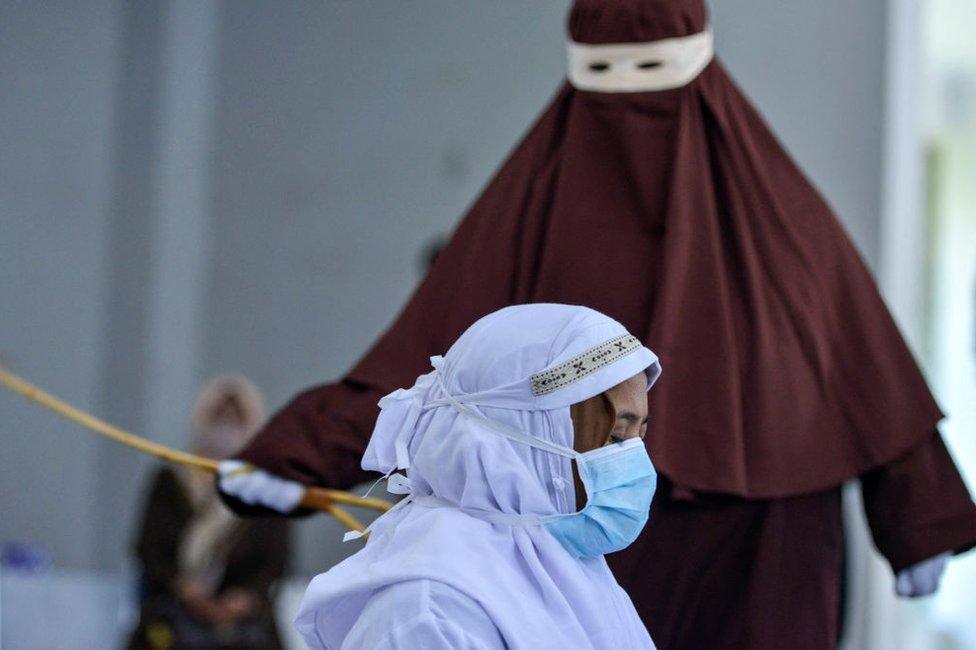 An Indonesian woman is publicly caned as punishment under Aceh province's Sharia laws for being caught with her boyfriend, in March 2021.